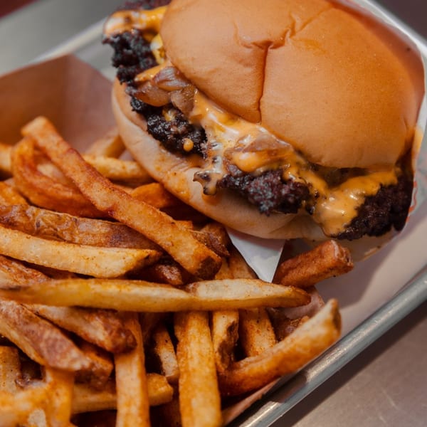 Cheeseburger with caramelized onions and melted cheese, served with a side of seasoned french fries.
