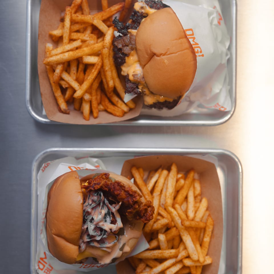 Two trays of burgers and fries, one with a beef burger, the other a fried chicken burger.