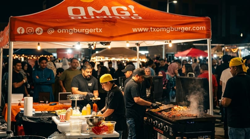 Chefs cook food on a griddle under an orange OMG! Burger tent at a busy night market.