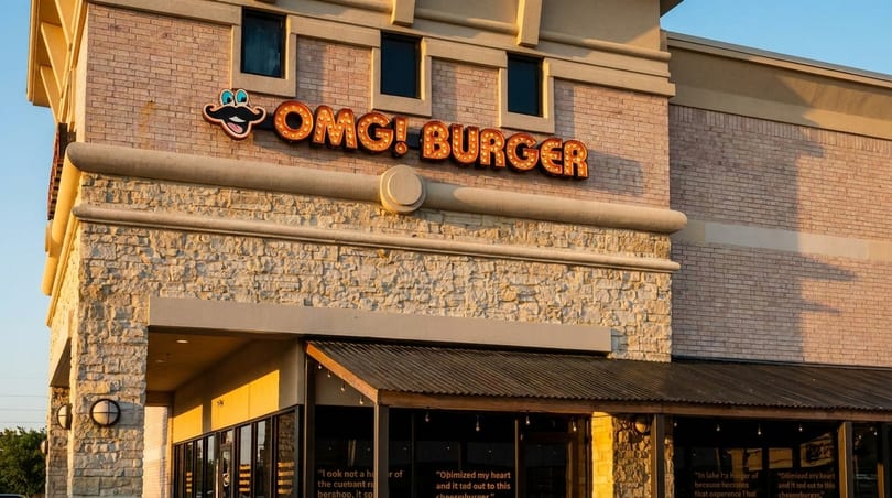 The exterior of OMG! Burger restaurant, featuring a brick and stone facade with a lighted sign.